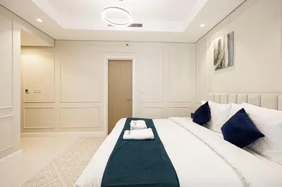 a bedroom with a large white bed with blue pillows at Boulevard 2 Bedroom Family Apartment with BURJ KHALIFA view and INFINITY POOL in 64th Floor Dubai Downtown in Dubai