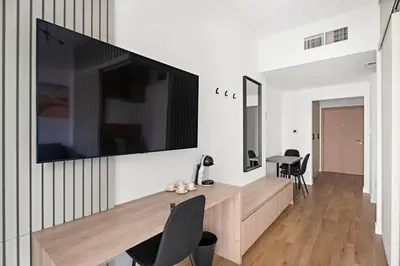 a living room with a large flat screen tv on a wall at Renovated Studio next to Dubai Mall & Burj Khalifa in Dubai