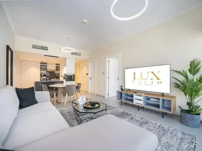 a living room with a white couch and a tv at Stylish Upgraded 1 Bedroom Marina Escape in Dubai