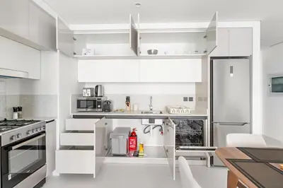 a kitchen with white cabinets and a refrigerator at Silkhaus Sea View 1BDR Exclusive Tower Beach in Dubai