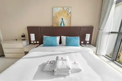 a bedroom with a white bed with towels on it at Stonetree - Brand New Studio - Prime Location in Dubai