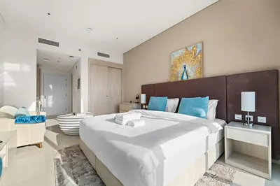 a bedroom with a large bed with blue pillows at Stonetree - Brand New Studio - Prime Location in Dubai