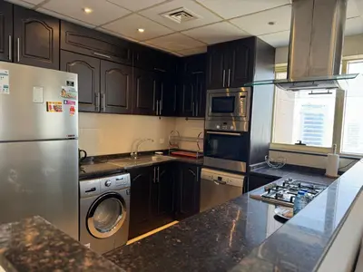 a kitchen with stainless steel appliances and black cabinets at Ashri HH, Studio in Dana Tower in Dubai