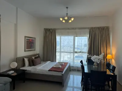 a bedroom with a bed and a table and a window at Ashri HH, Studio in Dana Tower in Dubai