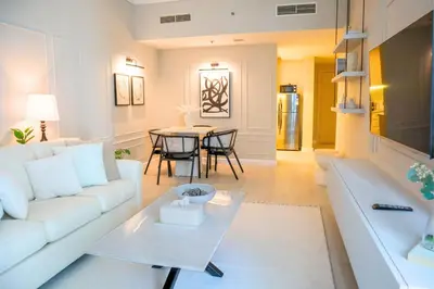 a living room with a white couch and a table at Spacious 1BR, Pool, Gym, Near Dining & Shops in Dubai