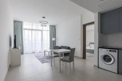 a kitchen and living room with a table and a washing machine at Splendid 1BR in Living Garden in Dubai