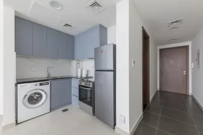 a kitchen with a refrigerator and a washing machine at Splendid 1BR in Living Garden in Dubai