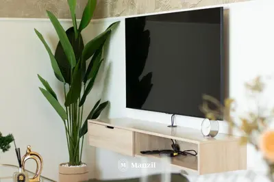 a television on a stand with a potted plant at Manzil - 1BR Apartment in Sobha Hartland with City Views in Dubai