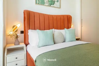 a bed with an orange headboard and blue pillows at Manzil - 1BR Apartment in Sobha Hartland with City Views in Dubai