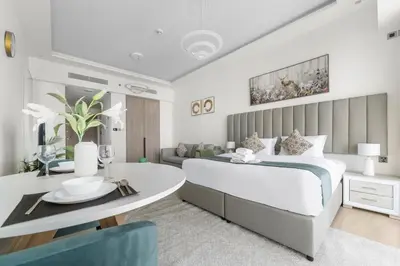 a bedroom with a large bed and a dining room at Stonetree - Brand New Studio - Prime Location in Dubai