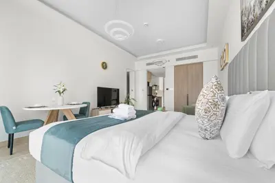 a bedroom with a large white bed and a table at Stonetree - Brand New Studio - Prime Location in Dubai