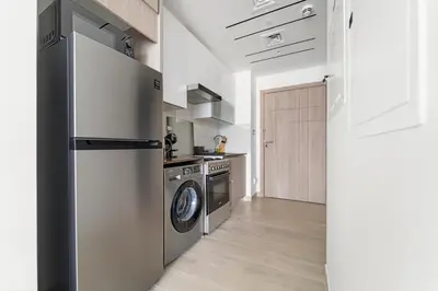 a kitchen with a refrigerator and a washing machine at Stonetree - Brand New Studio - Prime Location in Dubai