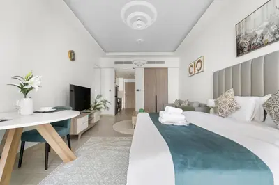 a bedroom with a large bed and a living room at Stonetree - Brand New Studio - Prime Location in Dubai