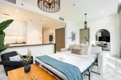 a living room with a white couch and a kitchen at Oraya - Sleek 1BR In District one , Direct Lagoon Access in Dubai