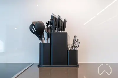 a black container filled with utensils on a table at Oraya - Sleek 1BR In District one , Direct Lagoon Access in Dubai