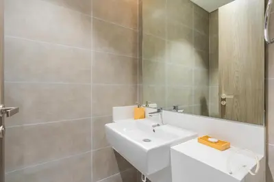 a bathroom with a white sink and a mirror at Oraya - Sleek 1BR In District one , Direct Lagoon Access in Dubai
