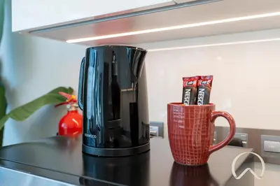 a black coffeemaker sitting on a counter with two cups at Oraya - Sleek 1BR In District one , Direct Lagoon Access in Dubai