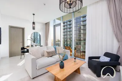 a living room with a white couch and a table at Oraya - Sleek 1BR In District one , Direct Lagoon Access in Dubai