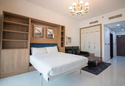 a bedroom with a large white bed and a chandelier at Furnished Studio Ready to Move-in in Dubai