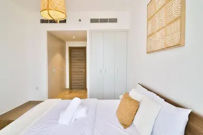 a bedroom with a bed with white sheets and pillows at Bohemian Bliss 1 BR Apartment in Dubai