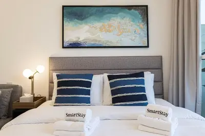 a bedroom with a bed with blue and white pillows at SmartStay at Carson Tower - Panoramic City Views - Modern Luxury Apartments in Dubai