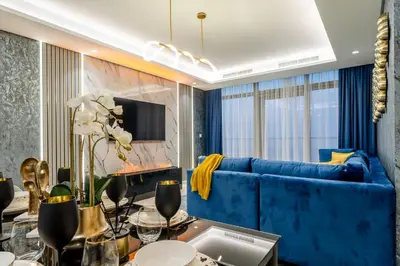 a living room with a blue couch and a table at Amazing 2BR Apartment in Paramount Hotel Midtown, 64th-Floor Infinity Pool & Burj Khalifa Views in Dubai