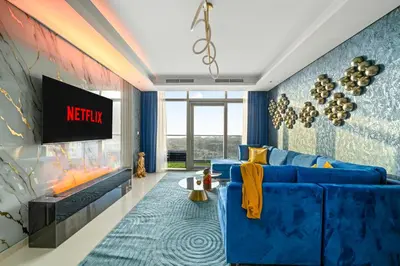 a living room with a blue couch and a tv at Amazing 2BR Apartment in Paramount Hotel Midtown, 64th-Floor Infinity Pool & Burj Khalifa Views in Dubai
