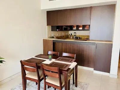 a dining room with a table and chairs and a kitchen at Greens in Dubai