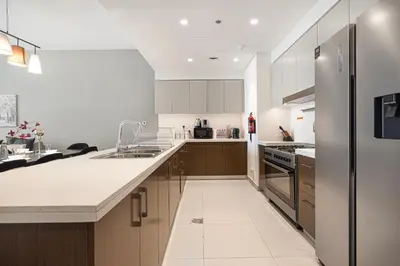a large kitchen with white cabinets and a refrigerator at Lux 3BR With Spectacular Downtown Views in Dubai