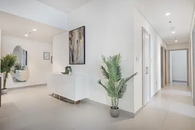 a white hallway with a table and a plant at Lux 3BR With Spectacular Downtown Views in Dubai