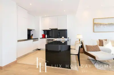 a living room with a couch and a chair and a kitchen at LUX The JW Marina Suite 2 in Dubai