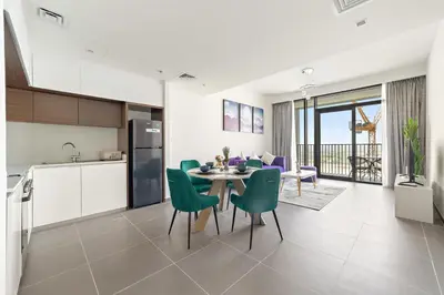 a kitchen and dining room with a table and green chairs at Elegant 1 Bedroom in Creek Edge in Dubai