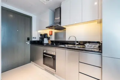a kitchen with white cabinets and a sink at ALiving Chic Studio Apartment I Partial Burj Khalifa & Canal View I DAMAC Maison Prive B- 1417 in Dubai