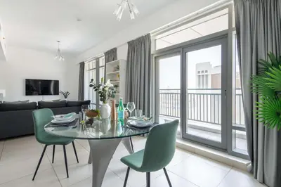 a living room with a glass table and green chairs at Frank Porter - The Lofts Central Tower in Dubai