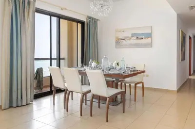 a dining room with a table and white chairs at Frank Porter - Sadaf 6 in Dubai