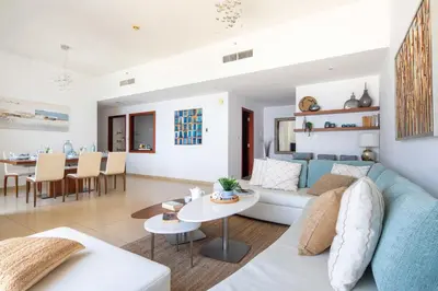 a living room and dining room with a blue couch at Frank Porter - Sadaf 6 in Dubai