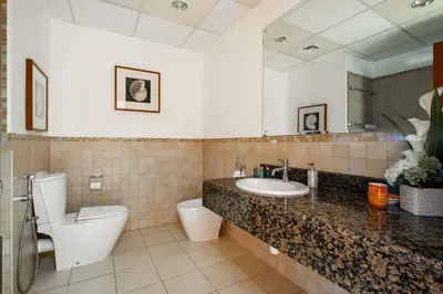 a bathroom with a toilet and a sink and a mirror at Frank Porter - Sadaf 6 in Dubai