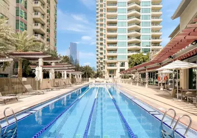 a large swimming pool with chairs and buildings at 2BR Dubai Marina Apt - Walk to Metro - Pool and Gym in Dubai