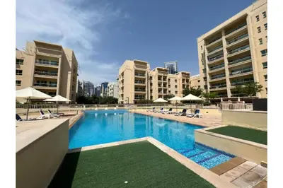 a large swimming pool with chairs and umbrellas at HAVN - 1 Bedroom in The Greens, Barsha Heights in Dubai