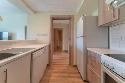 a kitchen with a white refrigerator and wooden floors at HAVN - 1 Bedroom in The Greens, Barsha Heights in Dubai