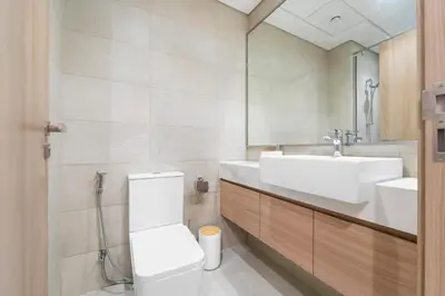 a bathroom with a sink and a toilet and a mirror at Lovely Studio with Gym, Pool and BBQ Facilities in Dubai
