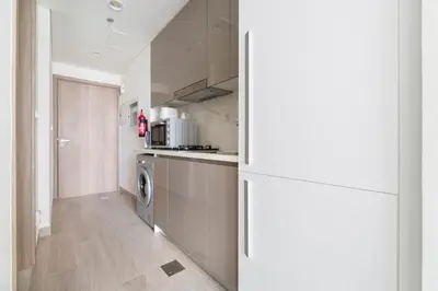 a kitchen with a refrigerator and a washer and dryer at Lovely Studio with Gym, Pool and BBQ Facilities in Dubai