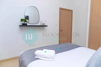 a bedroom with a bed with towels and a mirror at Bloomfields 1br Azizi Gardens Meydan in Dubai