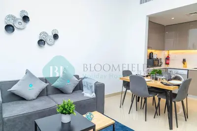 a living room with a couch and a table and a kitchen at Bloomfields 1br Azizi Gardens Meydan in Dubai