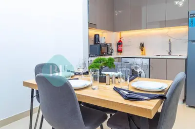 a kitchen with a wooden table with chairs around it at Bloomfields 1br Azizi Gardens Meydan in Dubai
