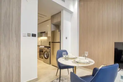 a dining room with a table and chairs and a kitchen at Elegant studio in Me Do Re Tower in Dubai