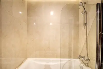 a bathroom with a shower and a white tub at Elegant studio in Me Do Re Tower in Dubai