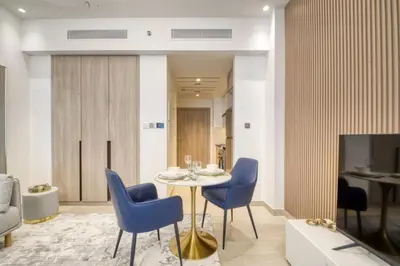a dining room with a table and blue chairs at Elegant studio in Me Do Re Tower in Dubai