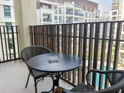 a table and chairs on a balcony with a view of a building at Elegant 1 Bedroom at Creek Beach Bayshore in Dubai