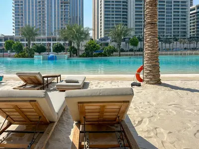 a resort with a pool with chairs and palm trees at Elegant 1 Bedroom at Creek Beach Bayshore in Dubai